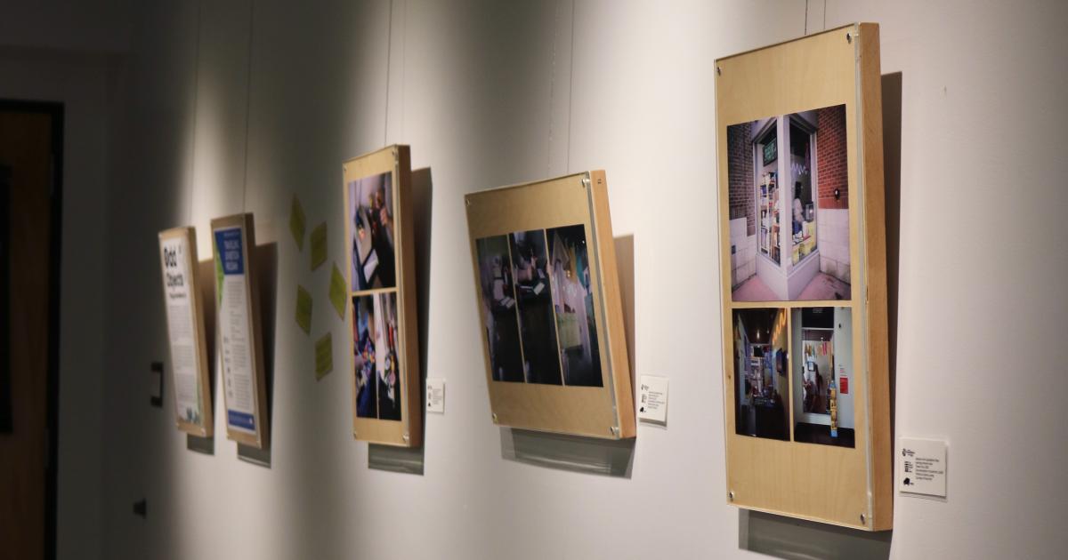 Five framed series of photos hang spotlighted on a white gallery wall. 