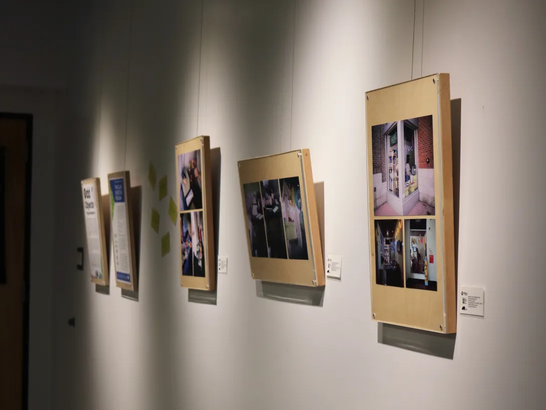 Five framed series of photos hang spotlighted on a white gallery wall. 